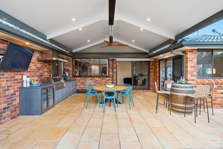 Modern pergola design with outdoor kitchen and dining setting, designed and built by Pergola Land — see pergolas like this at the Sydney showroom.