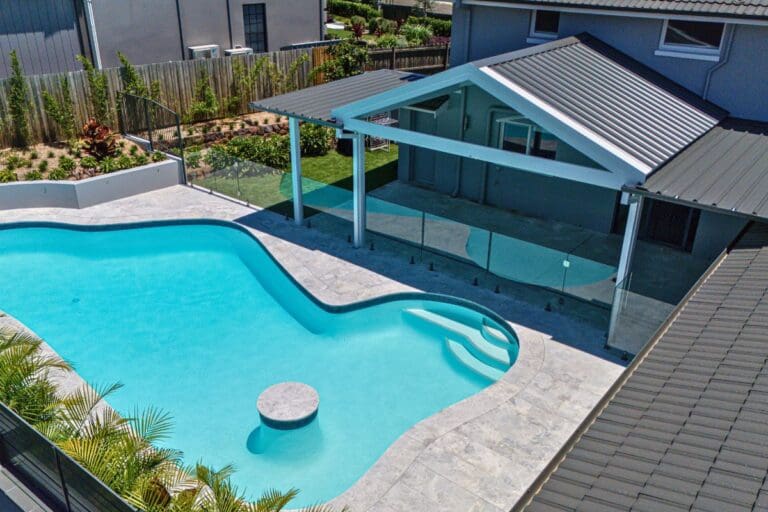 Contemporary patio extension with gable roof overlooking a modern pool, showing how a patio deck can enhance outdoor living. Designed and built by Pergola Land.